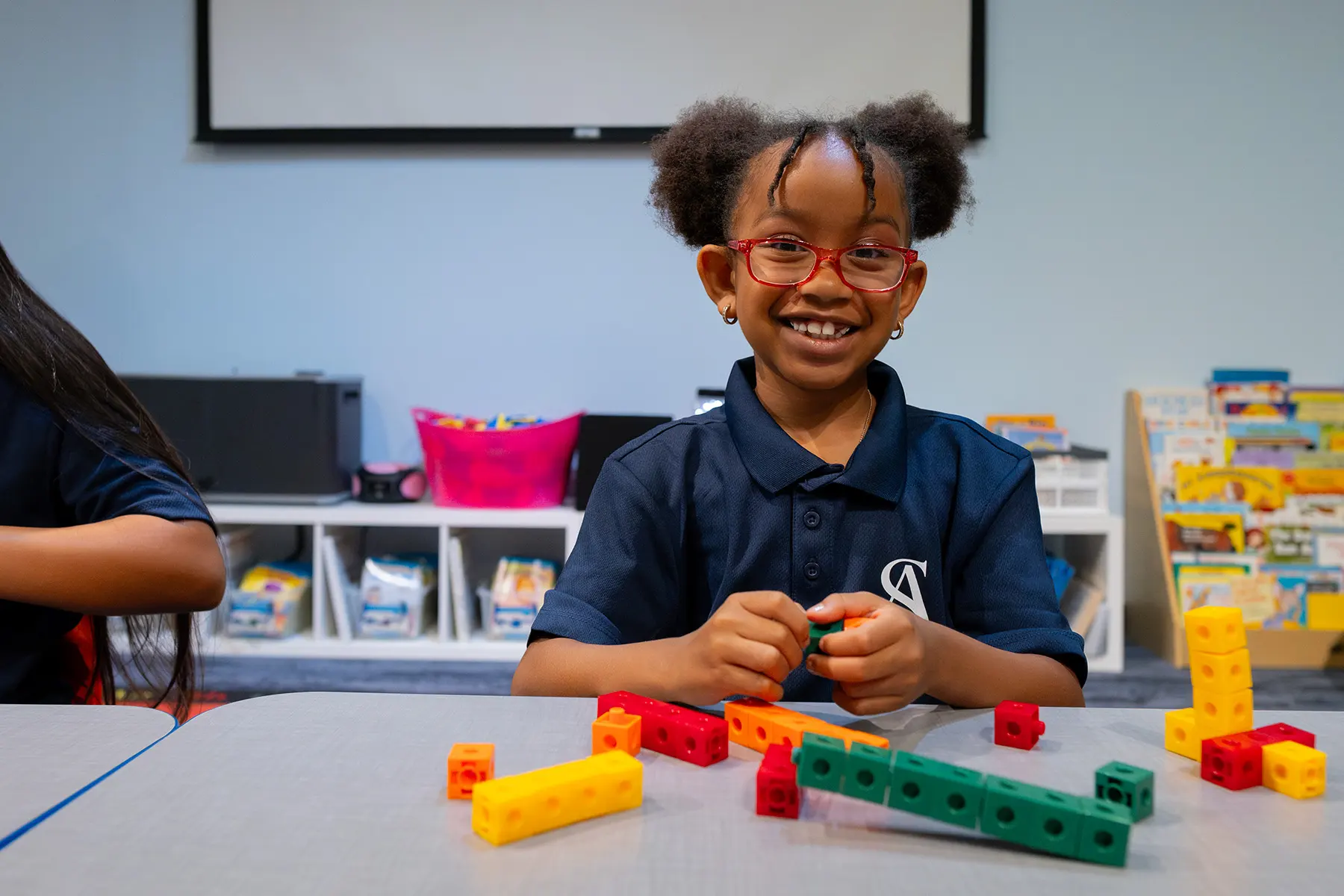 a little girl smiling at the camera while learning with blocks